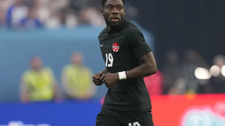 Canada winger Alphonso Davies stands on the field during a match