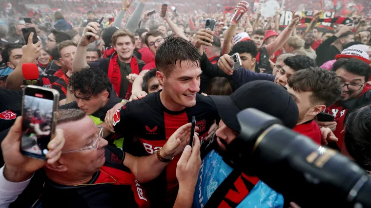 Patrik Schick surrounded by celebrating Bayer Leverkusen fans