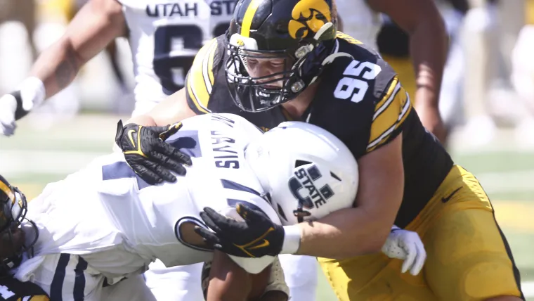 Defensive lineman Aaron Graves #95 of the Iowa Hawkeyes makes a tackle during the first half against wide receiver Micah Davis #4 of the Utah State Aggies at Kinnick Stadium on September 2, 2023 in Iowa City, Iowa